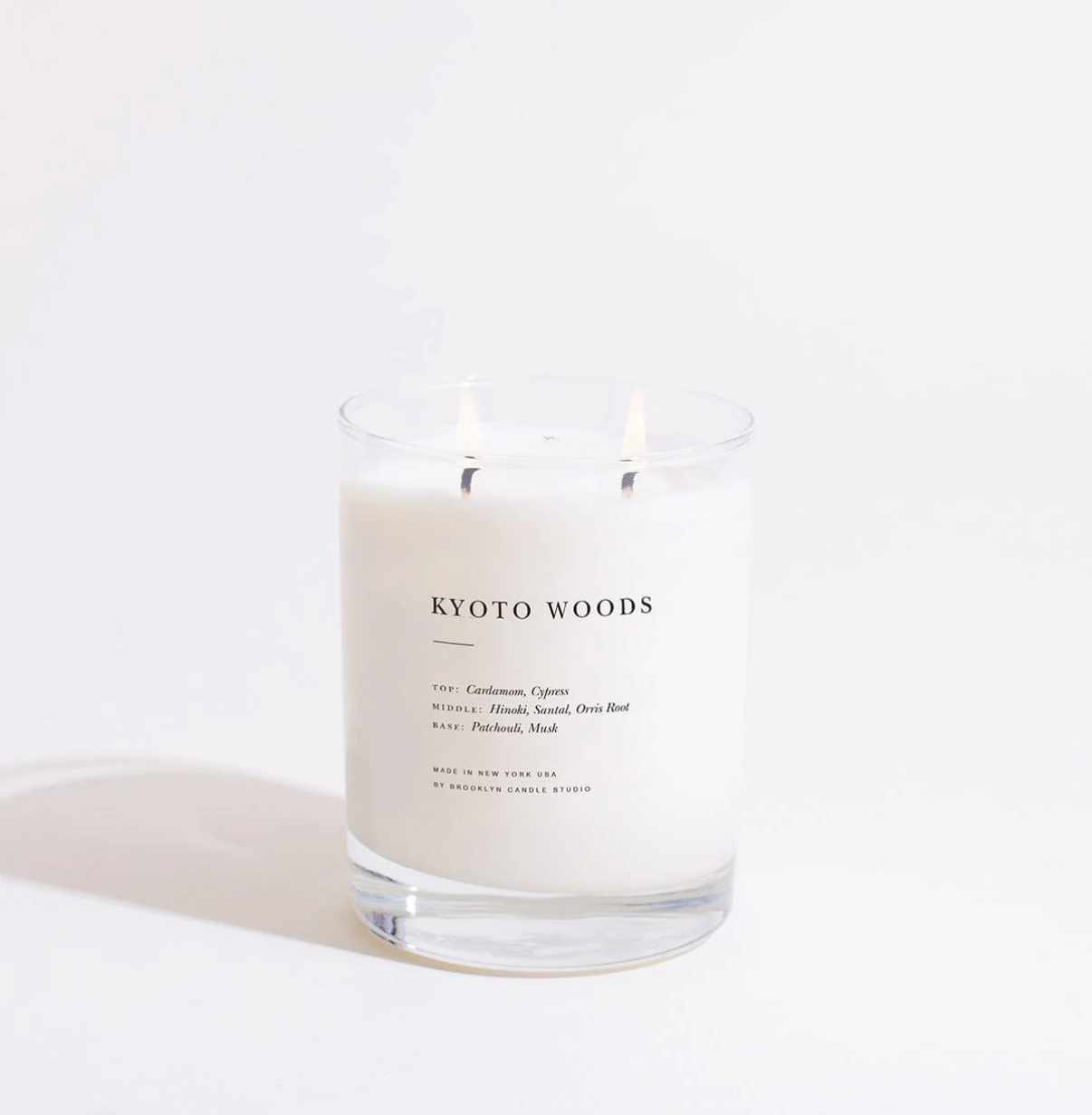 Candle labeled 'Kyoto Woods' on a white background