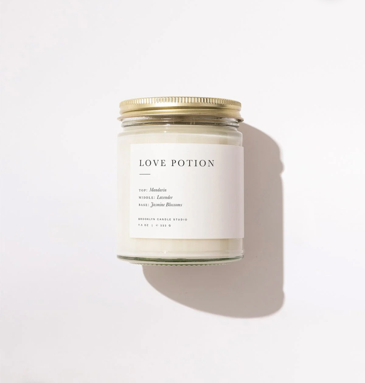 Candle labeled 'Love Potion' with a gold lid on a light background