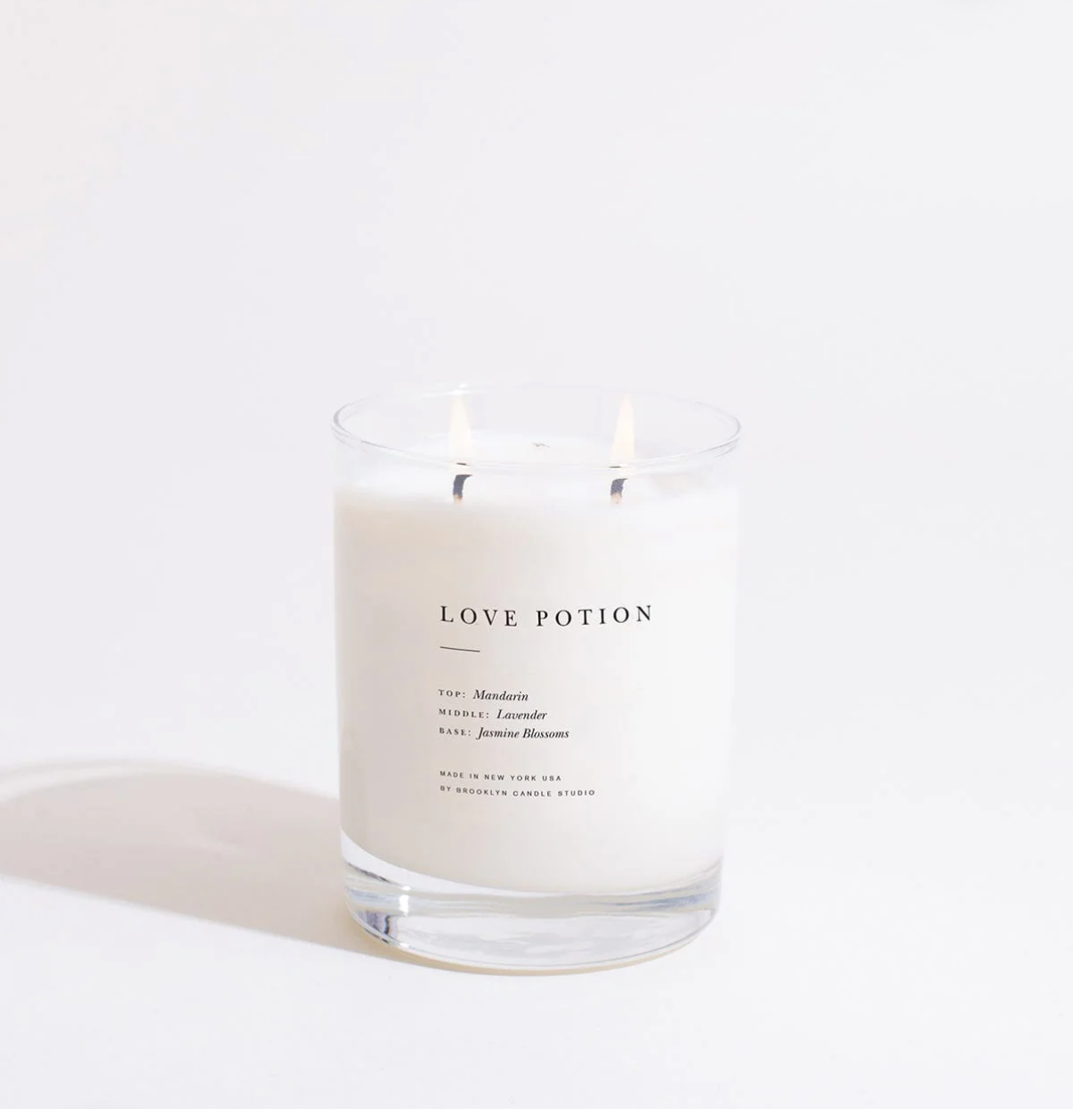 Candle in a glass jar labeled 'Love Potion' on a white background