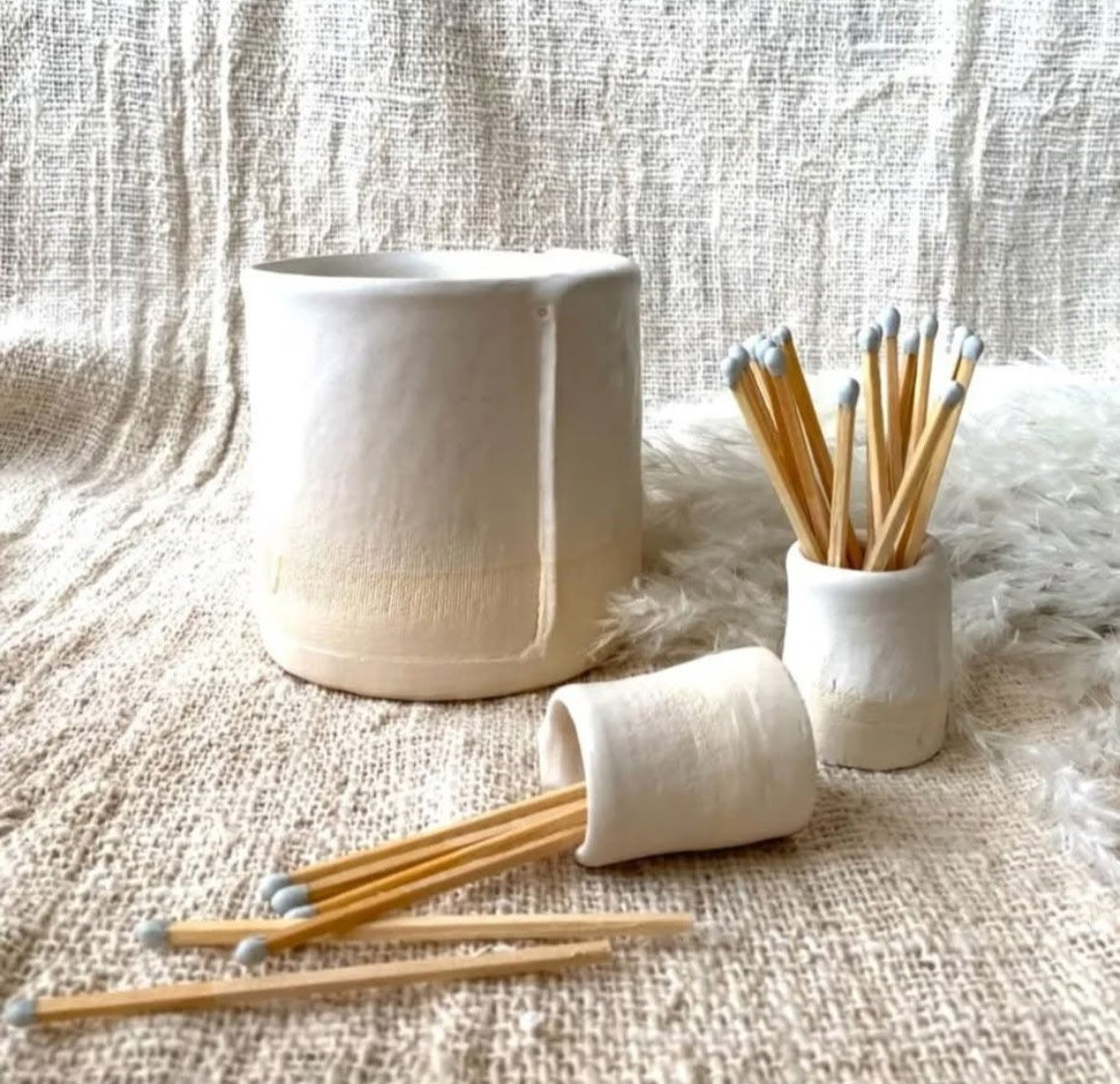 White ceramic containers with wooden sticks on a textured fabric background