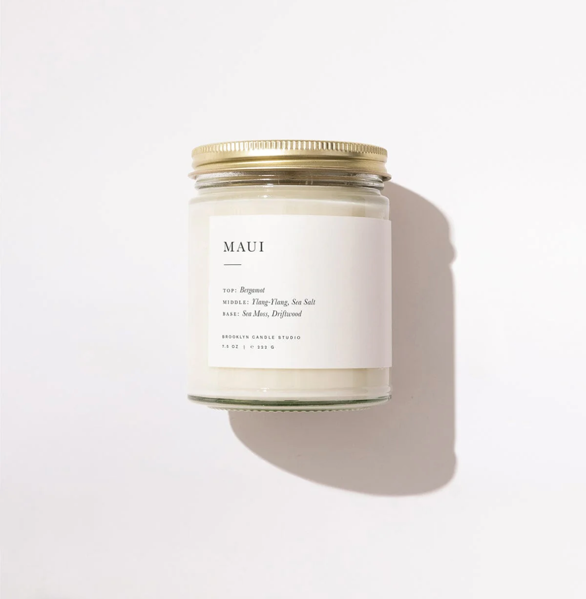 Candle jar labeled 'MAUI' with a gold lid on a white background
