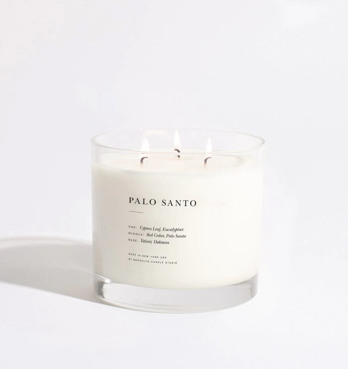 Palo Santo candle in a glass jar with a white label on a white background