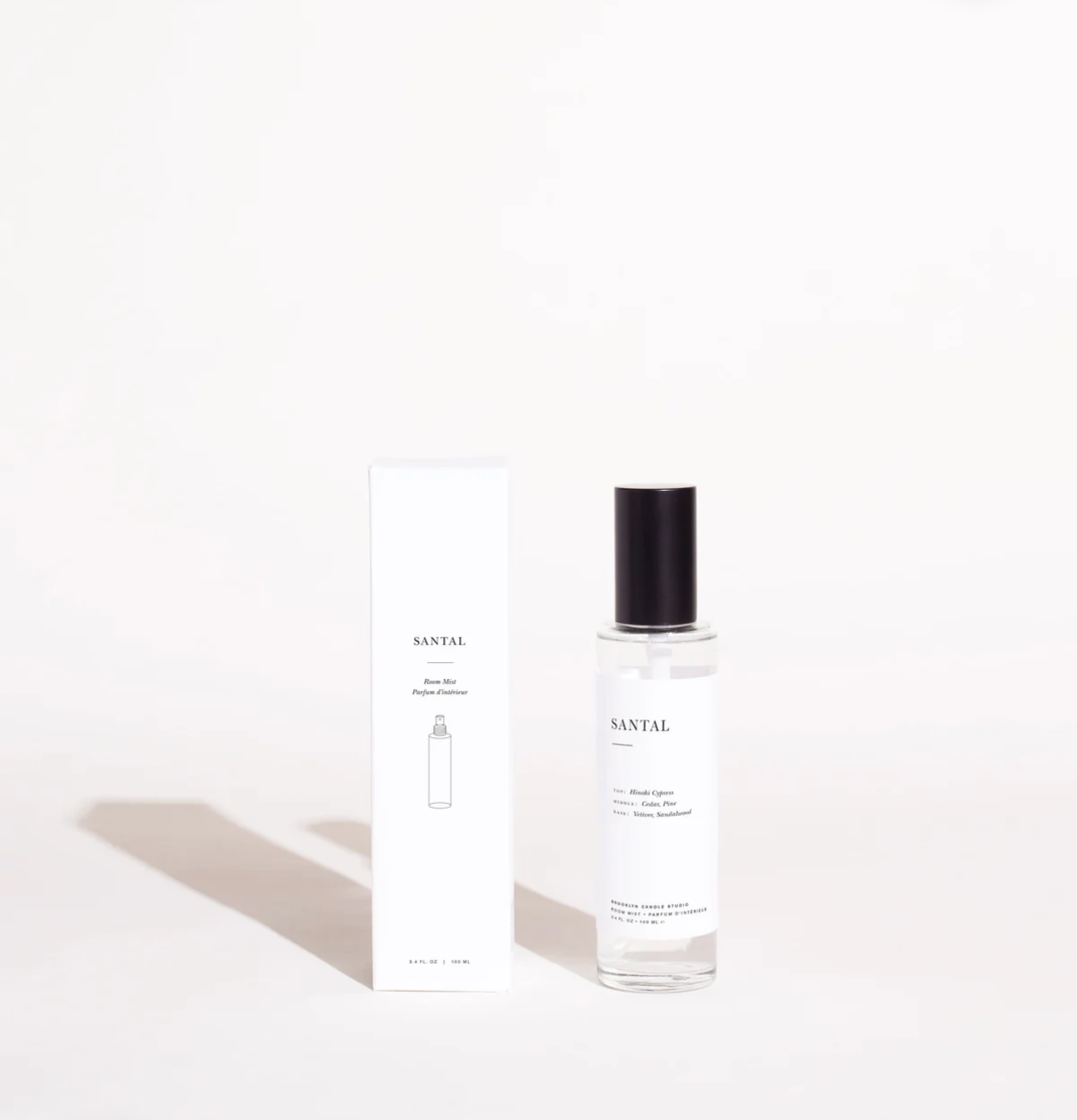 Perfume bottle with black cap and white label on a light gray background