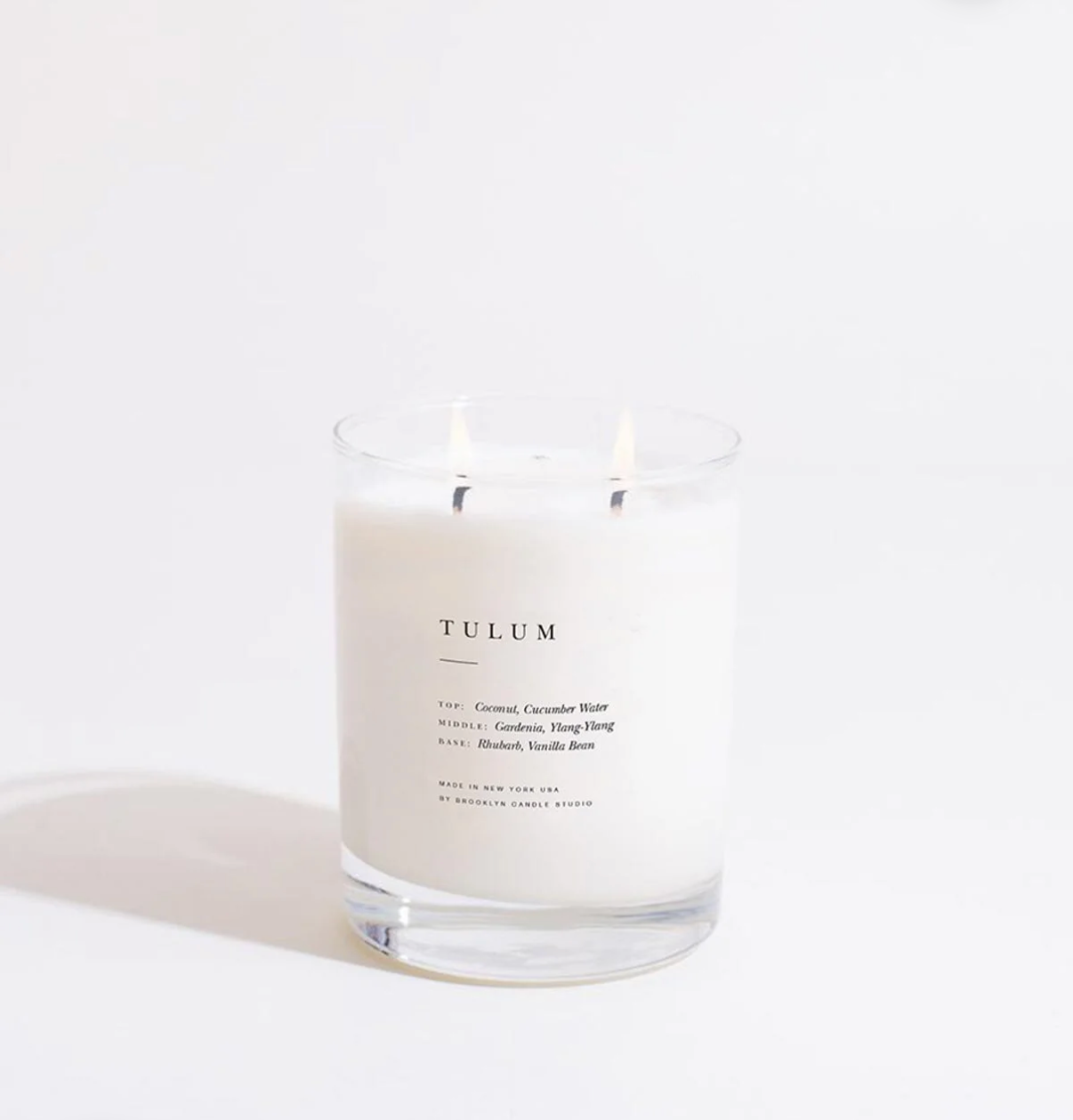 Candle in a glass jar labeled 'Tulum' on a white background